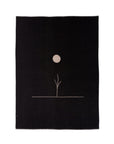 The Midnight Sun Throw Blanket by Blacksaw is a black rectangular textile crafted from eco-friendly sustainable fibers. It showcases a minimalist design with a thin line branching into a circular shape, resembling the sun or moon, and provides hypoallergenic comfort in reversible baby alpaca.