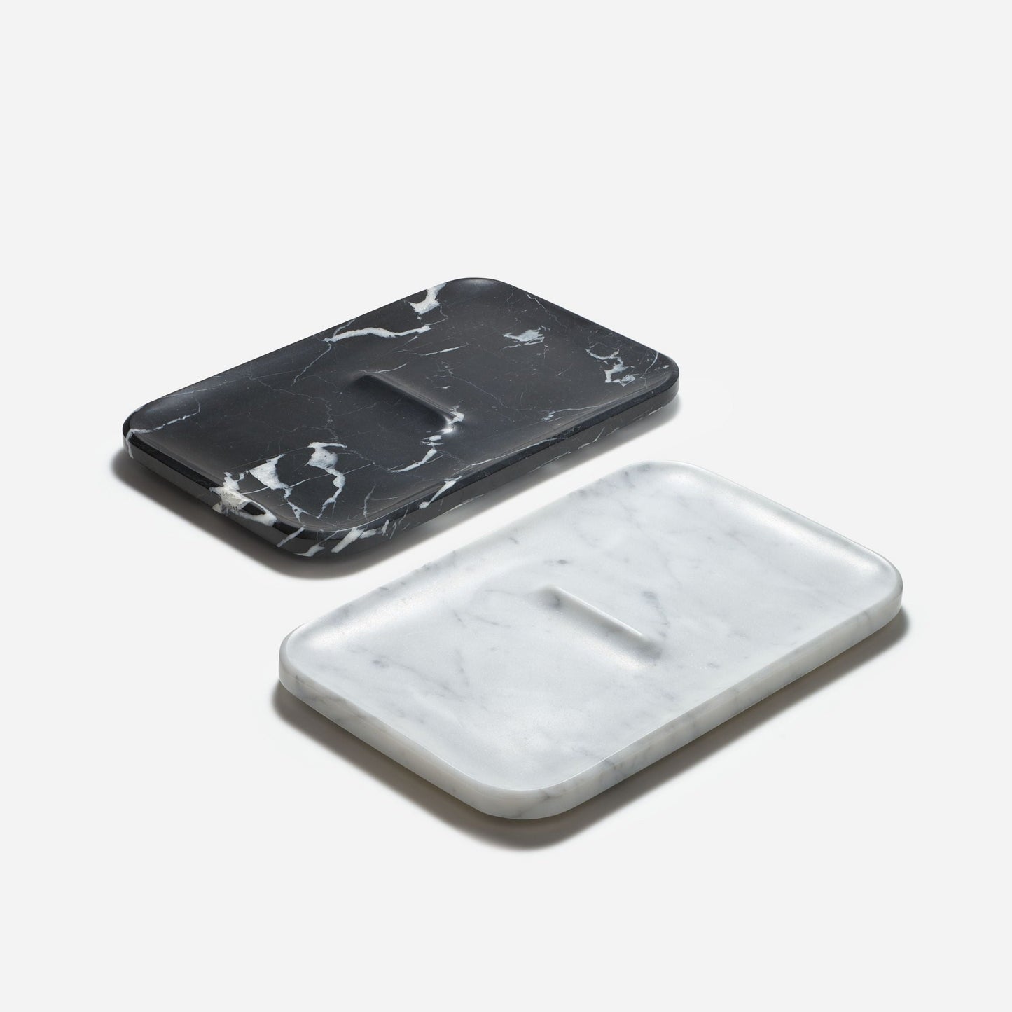 Two Craighill Marble Nocturn Catch trays are shown on a plain background; one is black with white veining, and the other is white with gray veining. Both feature dimensions highlighting their sleek design and have a small central rectangular indentation.