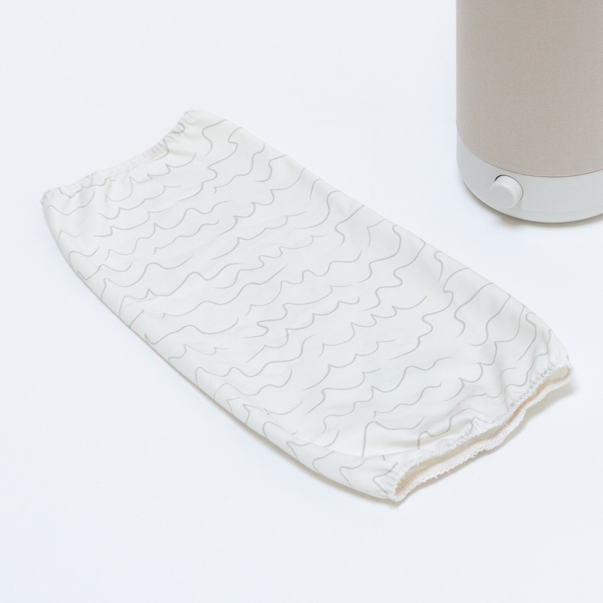 The Nightside Cursive Lines Cotton Shade (shade only) features white fabric with light gray wavy lines and elastic edges, shown next to a beige Nightside lamp, suggesting interchangeable shades for versatile style.