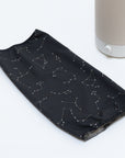 A Nightshade Starlight Cotton Blackout Shade by Nightside, with a constellation pattern, rests on a white surface next to a Nightside NS01 task lamp.