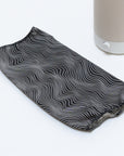 A black cotton Nightside Electric Flow Field Shade with white wavy lines is laid flat on a white surface, next to a cylindrical lamp base with a beige fabric shade and white button.