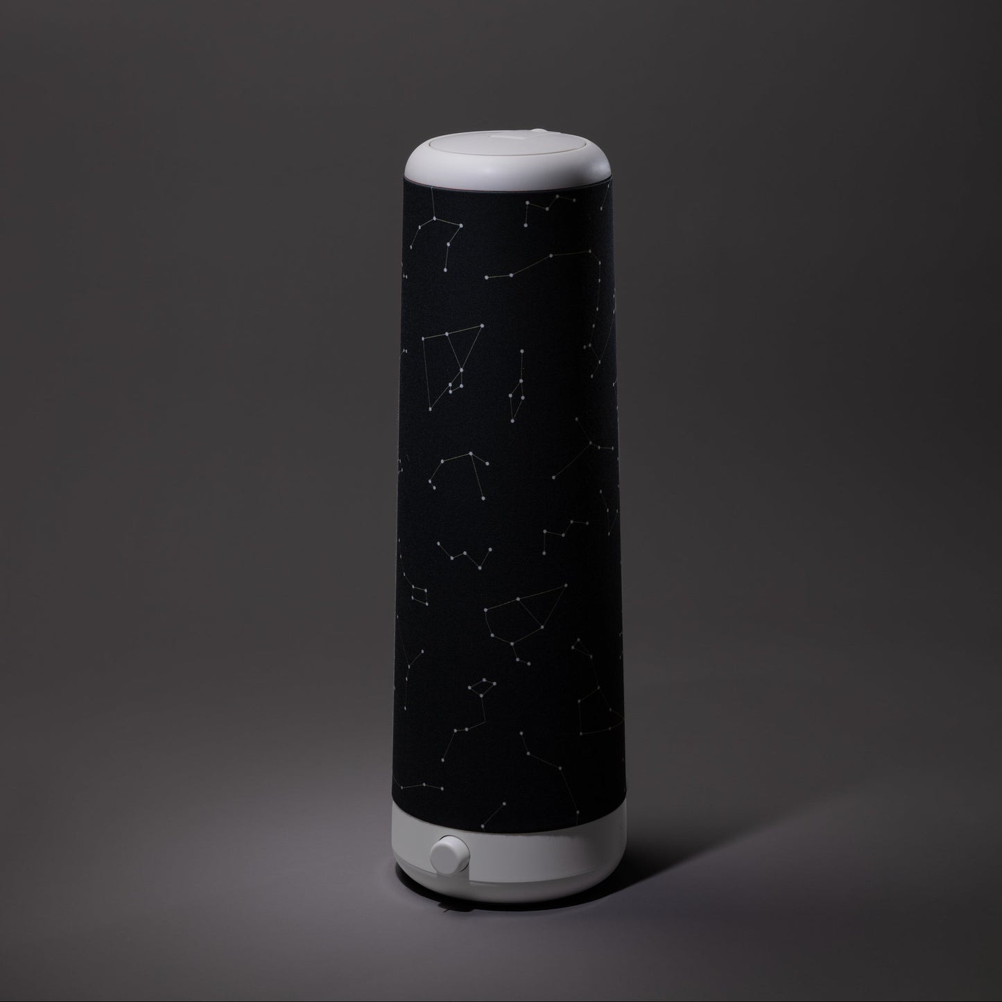 The Nightside Starlight Cotton Blackout Shade, shown with a bold constellation-patterned black fabric on a dark gray background, features interchangeable shades to match any blackout shade or décor style.