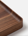 Close-up of the corner of the Ugmonk Valet Tray - Medium, a rectangular walnut tray with smooth, rounded edges and unique grain, displayed on a white surface.