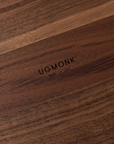 A close-up of a solid walnut surface engraved with UGMONK Made in USA shows a smooth texture and rich natural grain, crafted for the Ugmonk Valet Tray - Walnut Large.