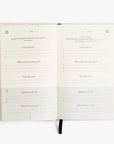 The Five Minute Journal by Intelligent Change lies open, inviting reflection with sections like I am grateful for... and Daily affirmation. This undated planner encourages introspection over 6 months, with a black ribbon bookmark guiding you through its 264 pages.