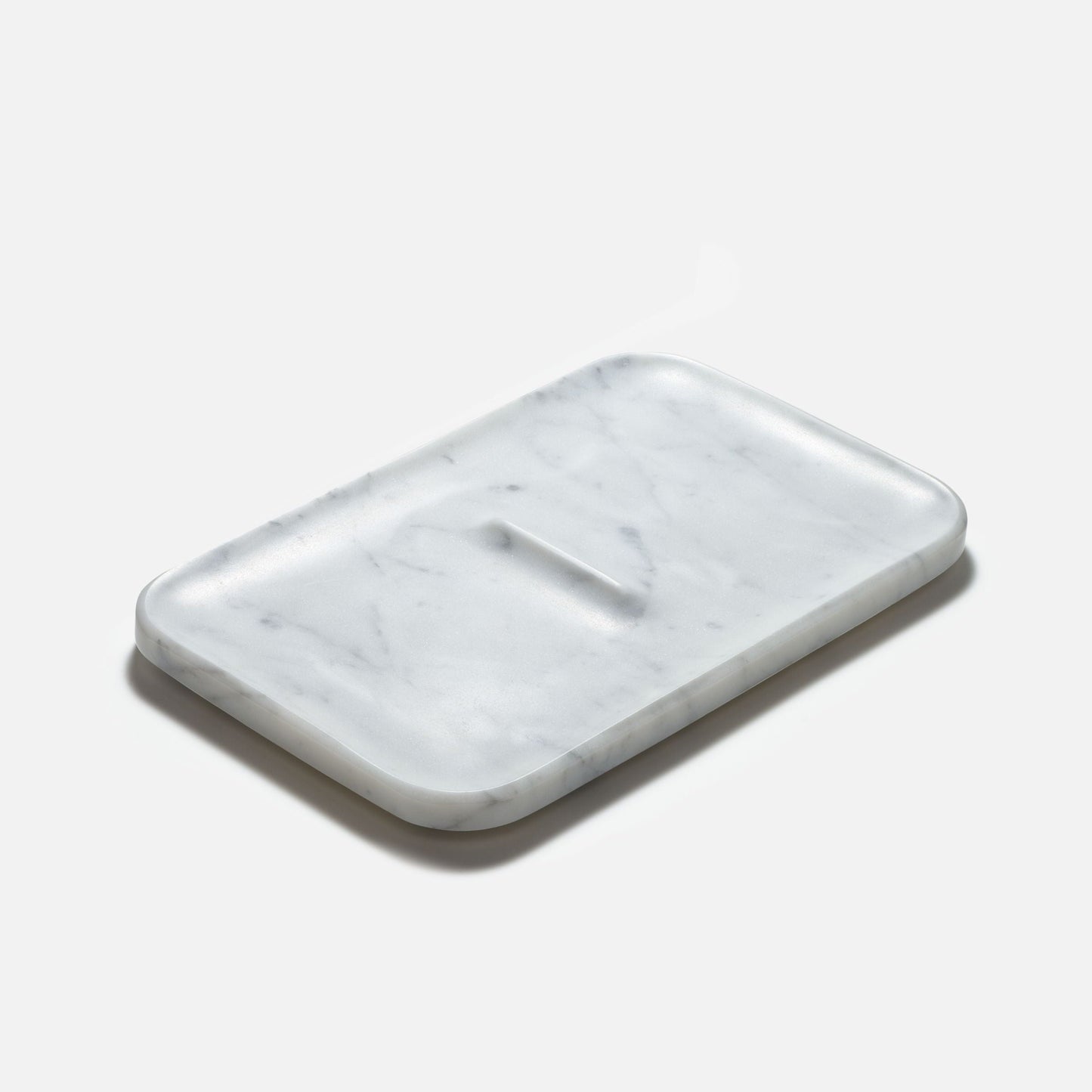 The Marble Nocturn Catch by Craighill is a rectangular tray with rounded edges crafted from white marble adorned with subtle gray veins.