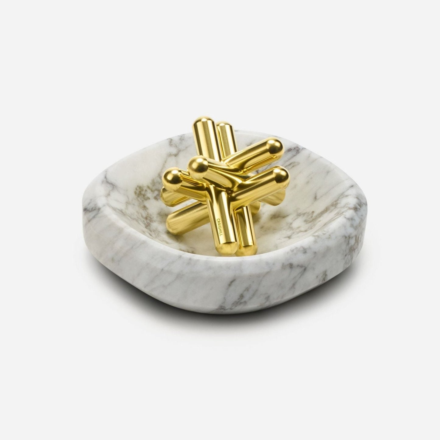 The Craighill Brass Jack Puzzle, made from solid brass, sits elegantly within a Craighill white marble Facet Bowl.