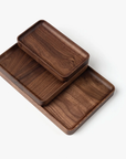 The Ugmonk Valet Tray Bundle (Walnut - Set of 3) is shown stacked together against a white background. Each handcrafted tray displays smooth, rounded edges and highlights the rich, natural walnut grain.
