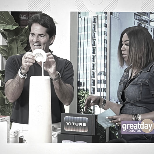 A man and woman marvel at the Nightside lamp during a news broadcast.