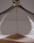 Close-up of the Intelligent Change Mindful Focus 30 Minute Hourglass, with sand trickling through its narrow center into a small pile below. The sharp focus and neutral background highlight its symbolism of mindful attention.