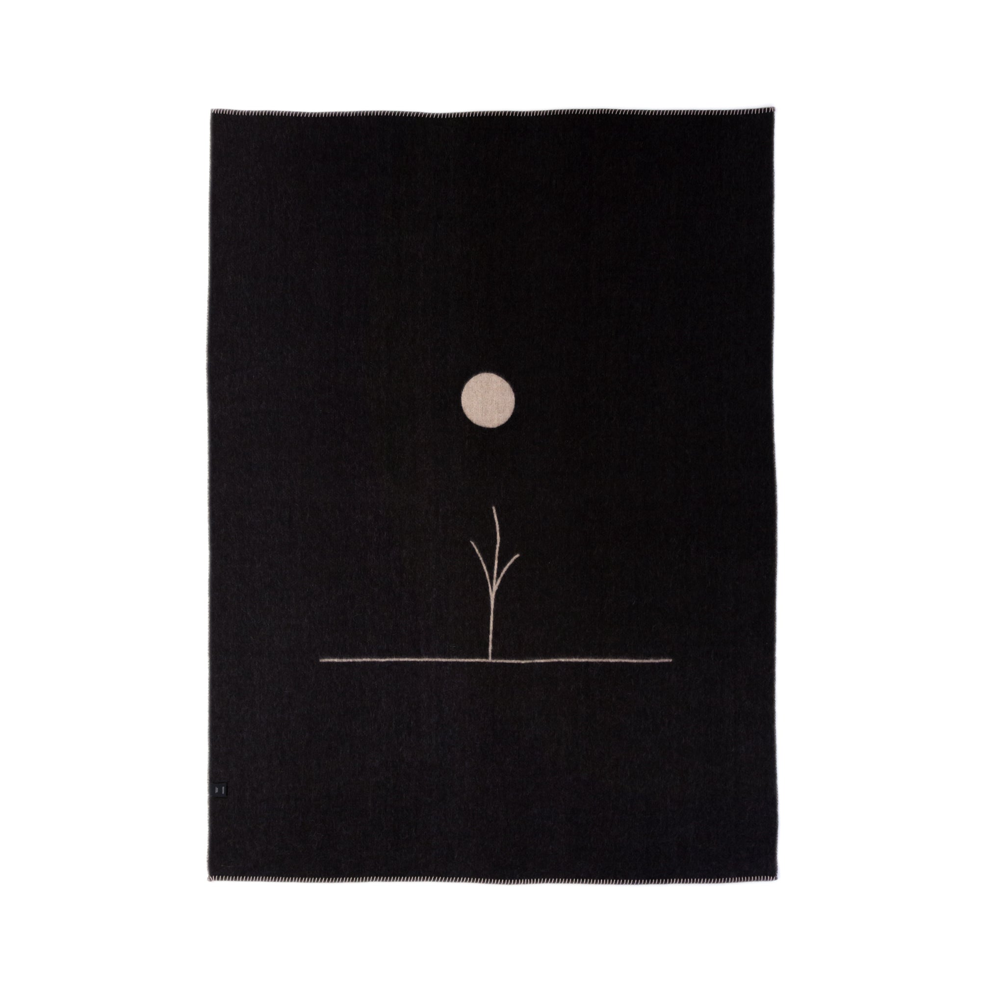 The Midnight Sun Throw Blanket by Blacksaw is a black rectangular textile crafted from eco-friendly sustainable fibers. It showcases a minimalist design with a thin line branching into a circular shape, resembling the sun or moon, and provides hypoallergenic comfort in reversible baby alpaca.