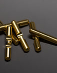 Several shiny, brass-toned metal cylinders with grooves lie scattered on a dark, reflective surface.