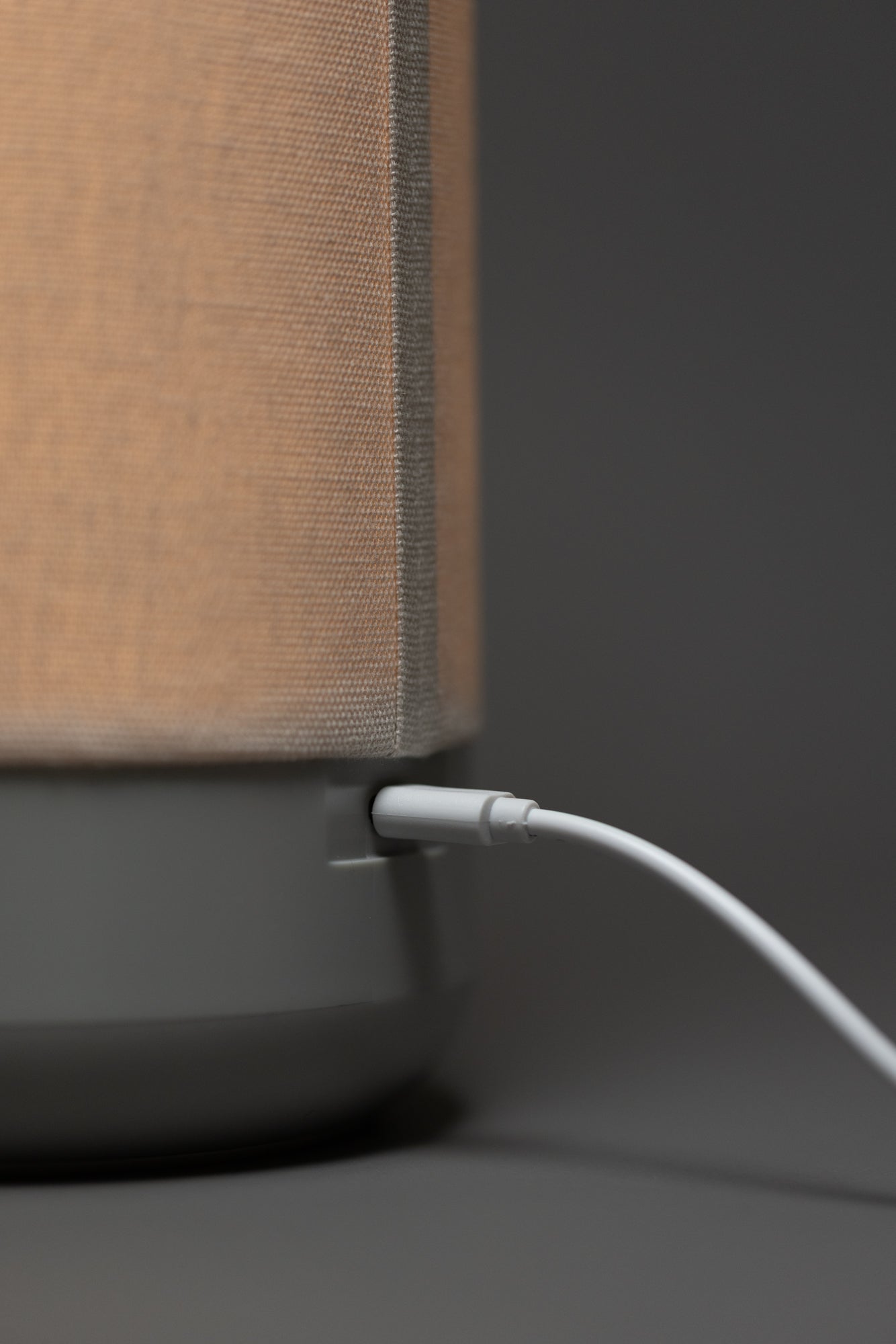 Closeup of a white USB cable plugged into the back of a gray lamp
