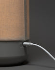 Closeup of a white USB cable plugged into the back of a gray lamp