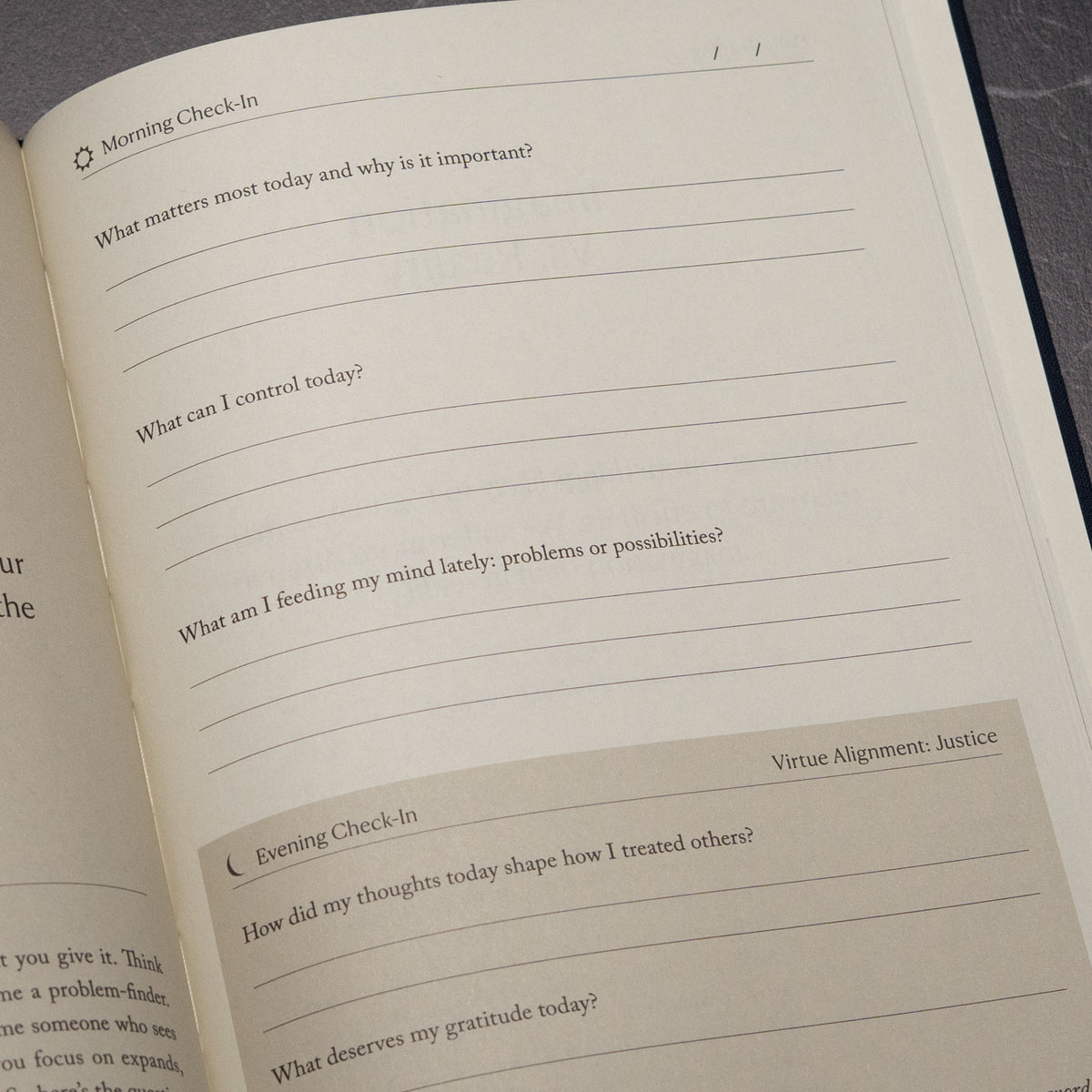 The Stoic Journal by Intelligent Change lies open, displaying morning and evening check-in prompts about intentions, control, mindset, interactions with others, and gratitude. The page is blank and ready to be filled in.
