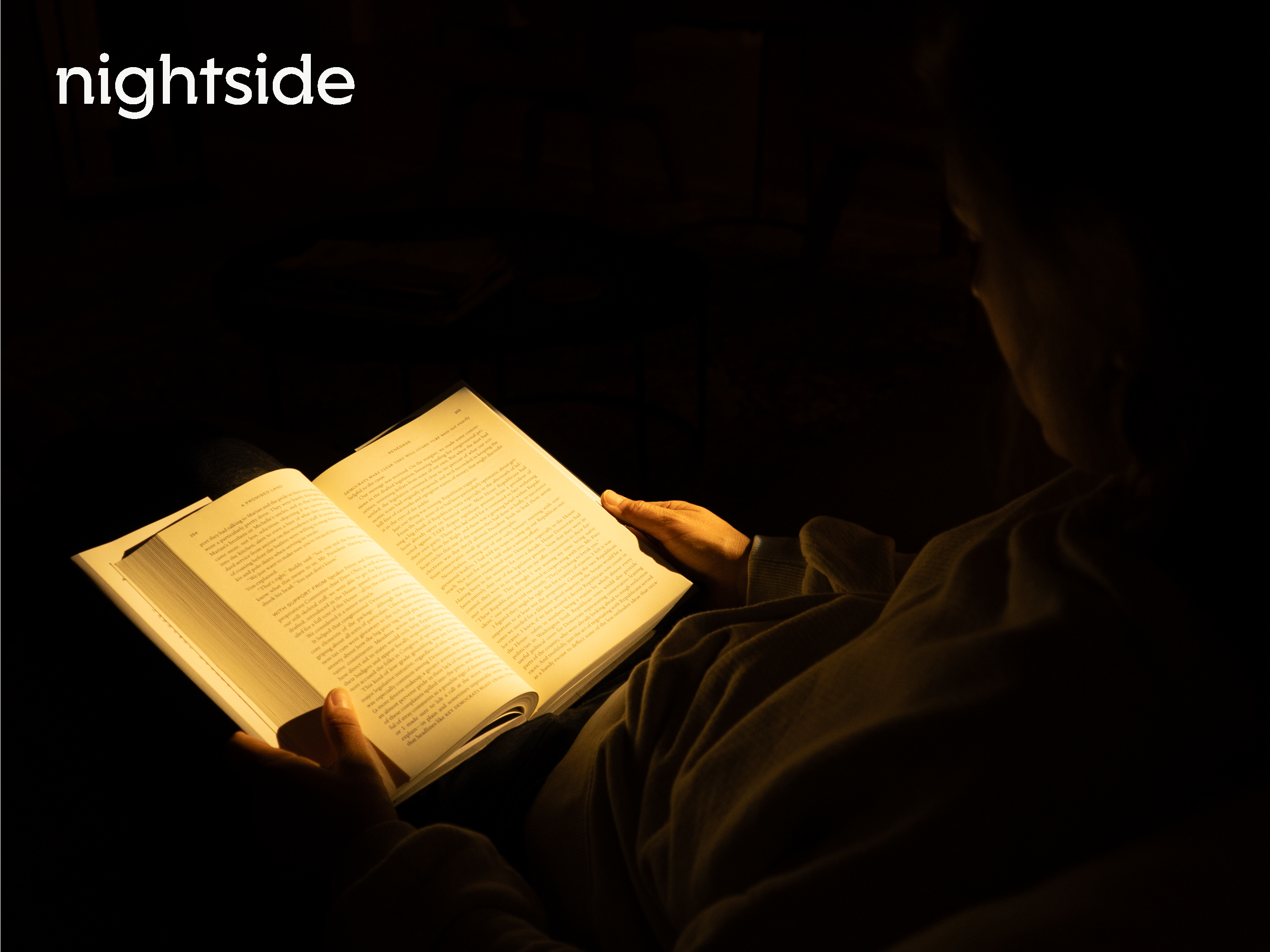 A person sitting in the dark reads a book illuminated by warm light. The word nightside is in the top left corner.