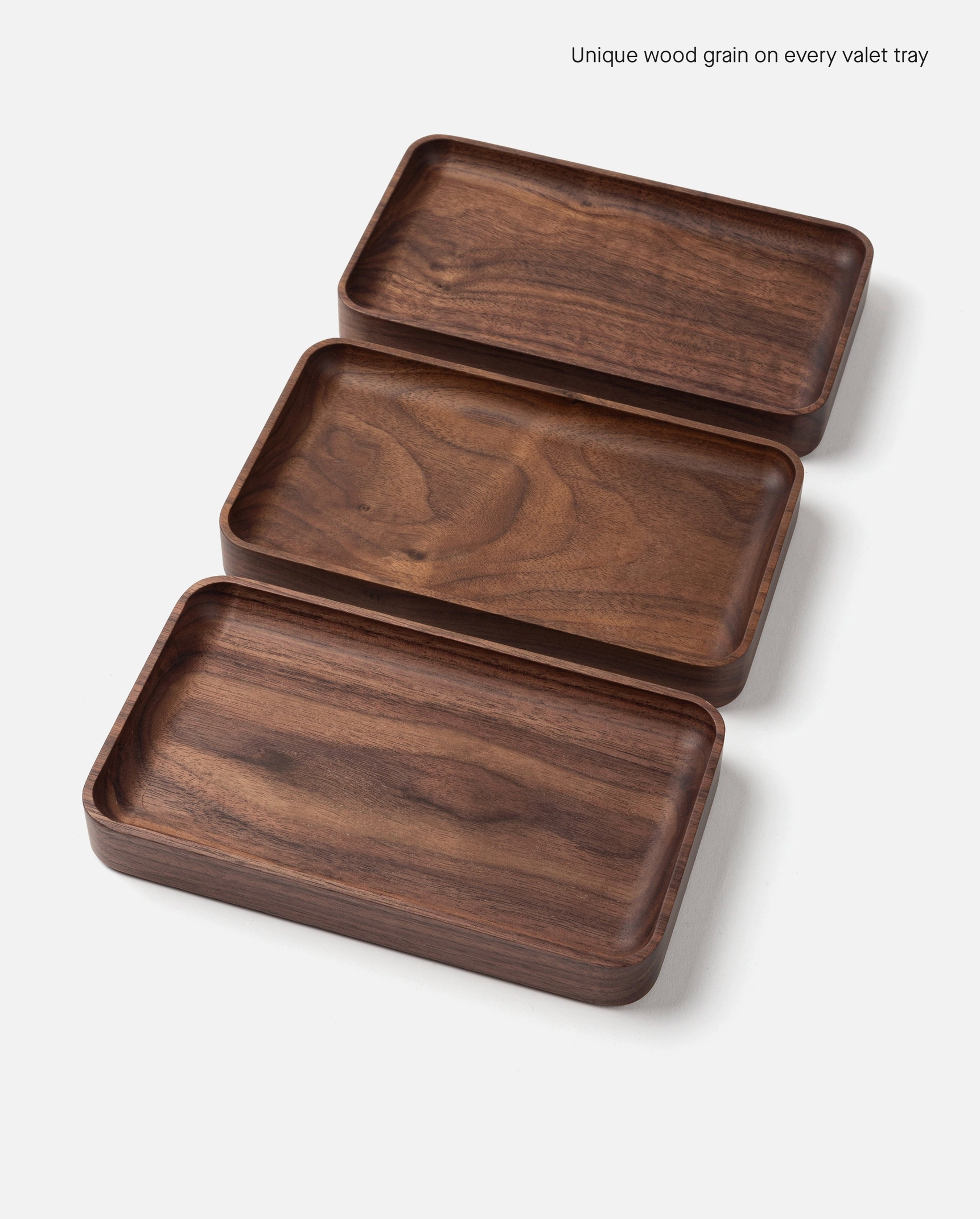 Three Ugmonk Valet Tray - Small pieces, handcrafted from solid walnut, are displayed in a staggered arrangement on a white background to showcase the unique wood grain of each tray.