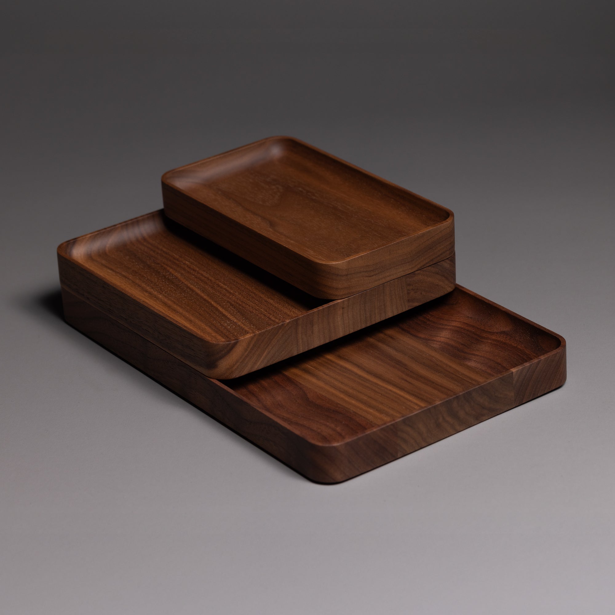The Ugmonk Valet Tray Bundle features three handcrafted solid walnut trays in varying sizes, stacked to display their smooth, rounded edges and natural grain—an elegant solution for organizing your essentials.